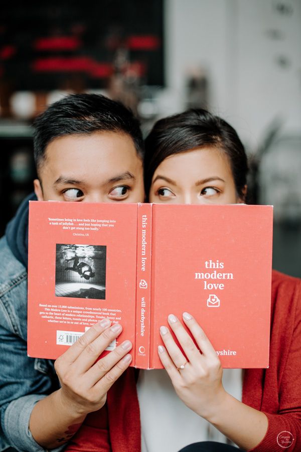 a man and woman holding up two red books with the words this modern love written on them