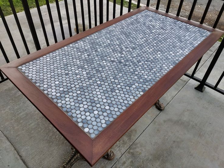 a table that is sitting on the sidewalk near a fence and some black iron railings