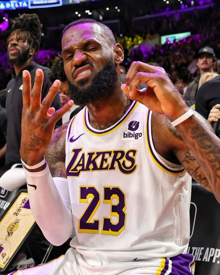 the lakers's lebrone is sitting on the bench with his hands in the air