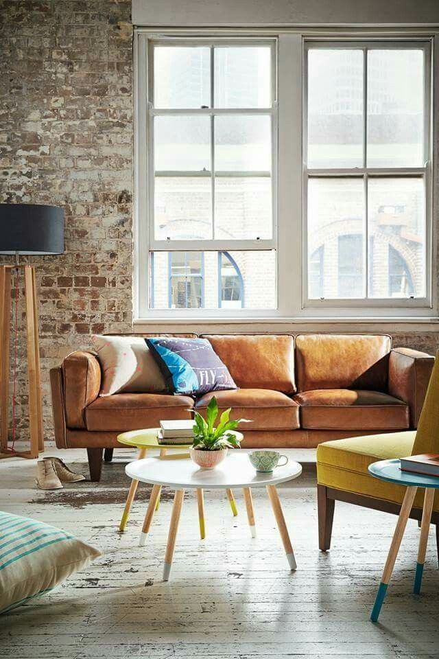 a living room with two couches and a coffee table in front of a brick wall