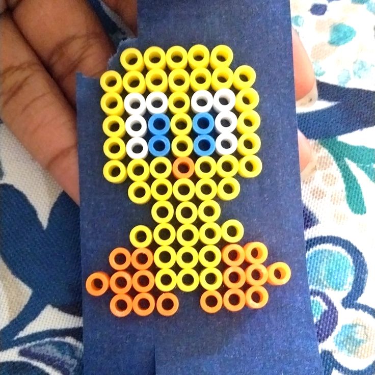 a hand holding a piece of blue material with yellow and white circles on it, in the shape of a rocket ship