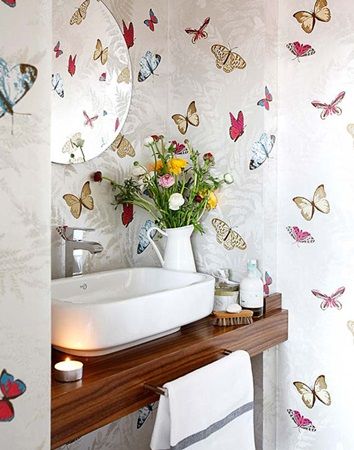 a bathroom with butterflies on the wall and a white sink in front of a mirror