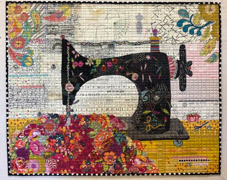 an old sewing machine sitting on top of a patchwork piece of cloth with colorful flowers