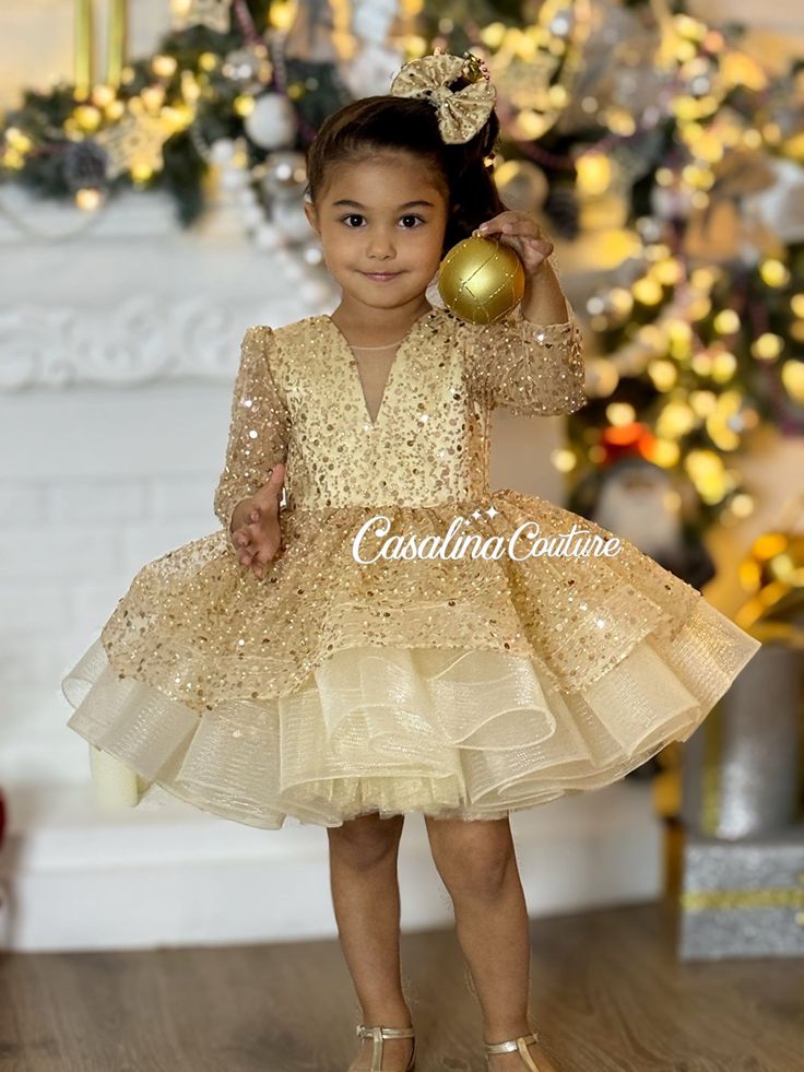 Introducing the Glamorous Gold Rihanna Dress for Baby Girls Elevate your baby girl's style with our exquisite Gold Rihanna Dress, a knee-length, voluminous ensemble that radiates brilliance, perfect for any special occasion. This resplendent dress is a captivating choice, designed to make your little one feel like a princess. The Gold Rihanna Dress features a stunning interplay of fabrics, with dazzling sequins adorning the entirety of the gold base. The long sleeves and V-shaped neckline add a touch of sophistication, creating a regal look that will transform your daughter into a little princess. The dress's enchanting silhouette is complemented by a charming and adorable hair accessory, adding a touch of sweetness to the overall look. Each Gold Rihanna Dress is a unique masterpiece, tail Gold Princess Dress, Rihanna Dress, Dress Baby Girl, Dress Gold, Dress Picture, Color Dorado, Gold Dress