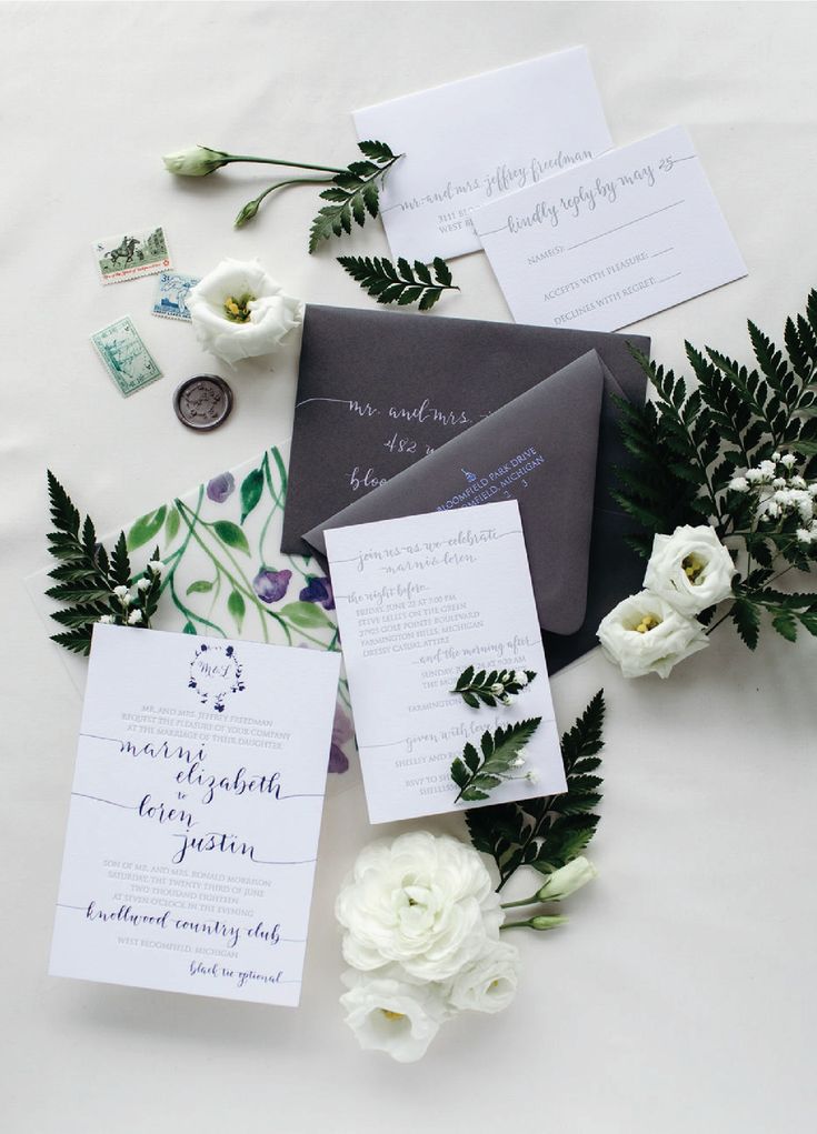 the wedding stationery is laid out on top of the table with white flowers and greenery