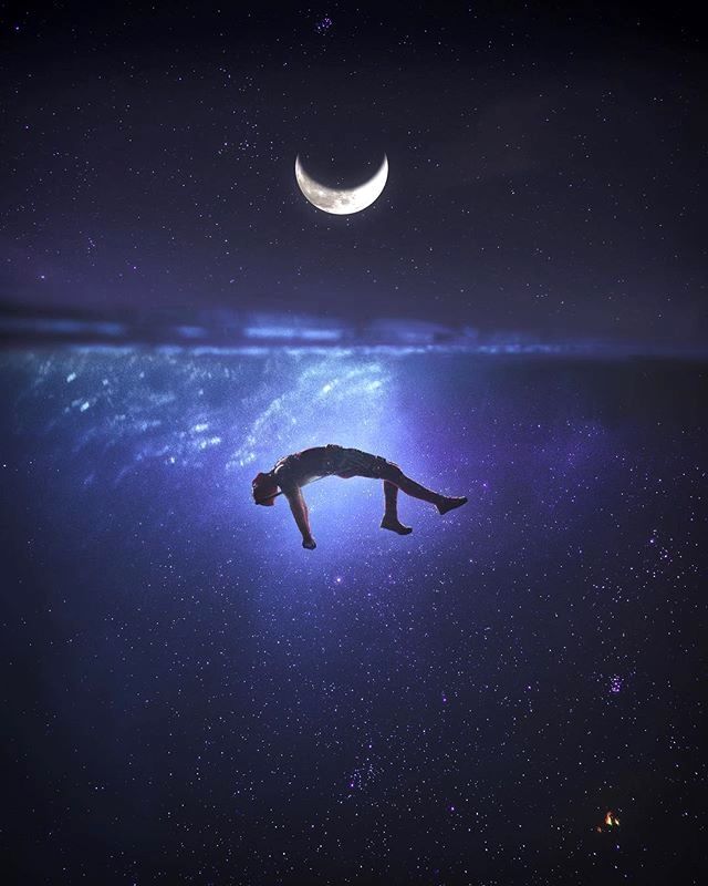 a man is floating in the water at night with a half moon above his head