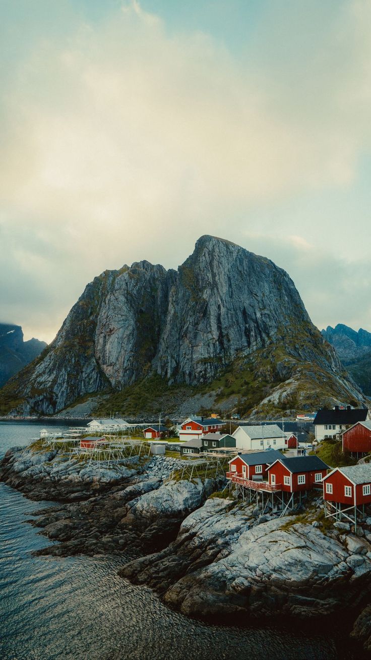 an island with red houses and mountains in the backgrouds, surrounded by water