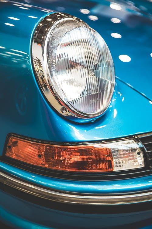 the front end of a blue car with a light on it's headlight