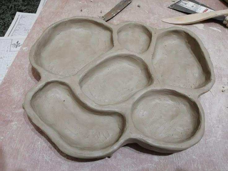 a cement tray with six sections on top of it and a pair of scissors next to it