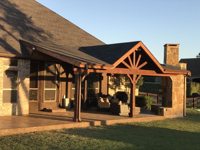 a covered patio in front of a brick house