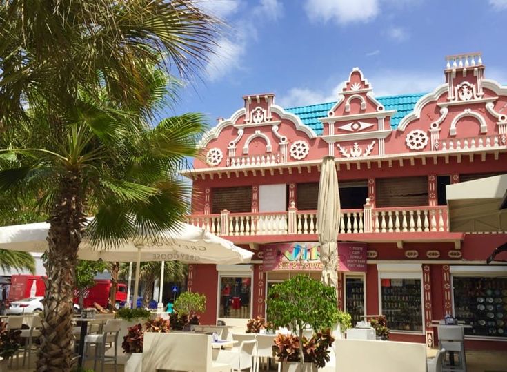 a red building with white balconies and palm trees