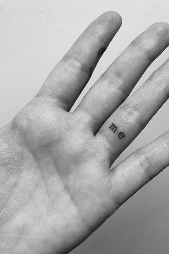 a person's hand with a small tattoo on the middle of their left palm