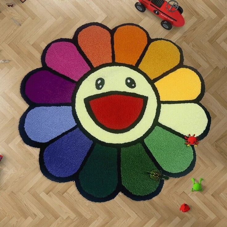 a multicolored rug with a smiling face on the floor next to toy cars