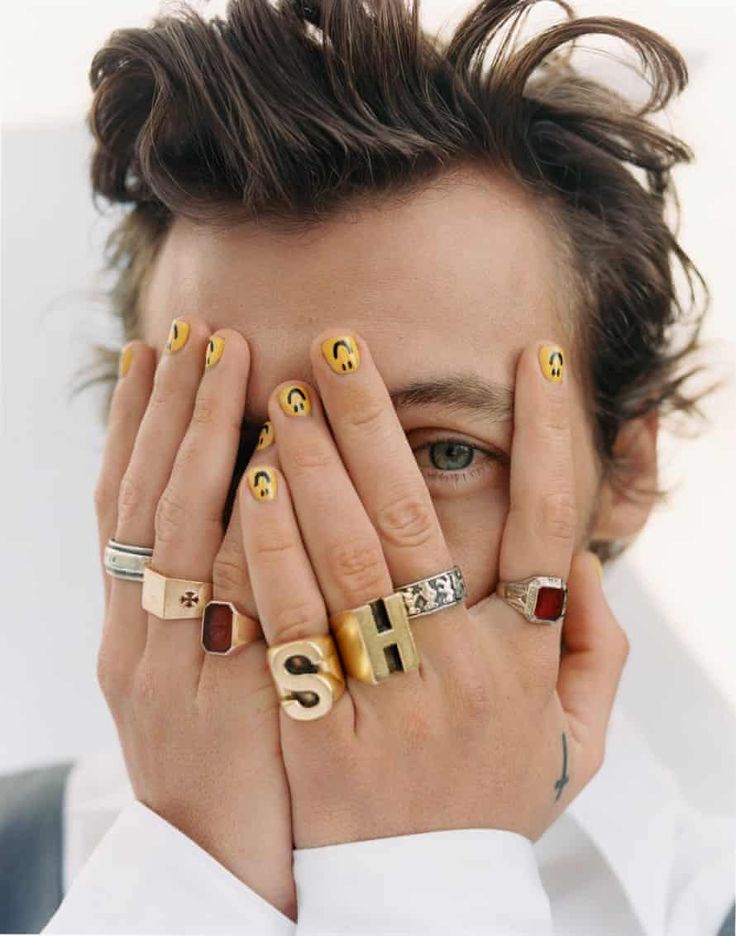 a man holding his hands to his face with different rings on it's fingers