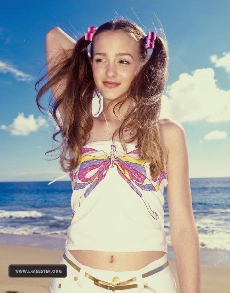 a young woman standing on top of a beach next to the ocean wearing headphones