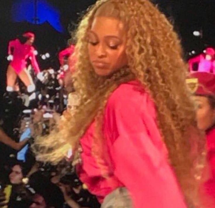 a woman with long blonde hair standing in front of a crowd