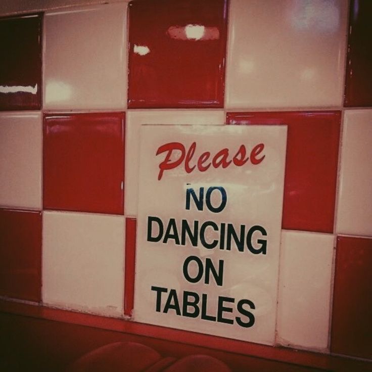 a sign that says please no dancing on tables in front of red and white tiles