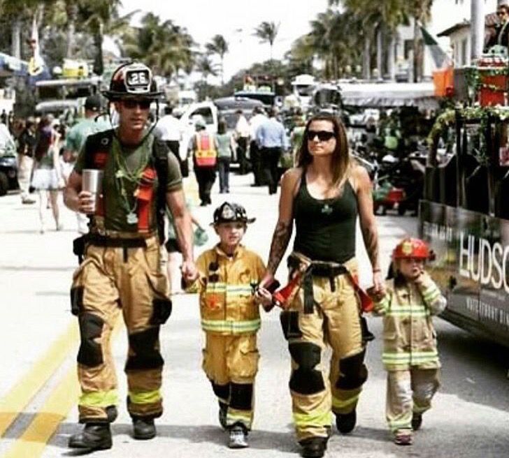 a woman and two children are walking down the street in front of a firetruck