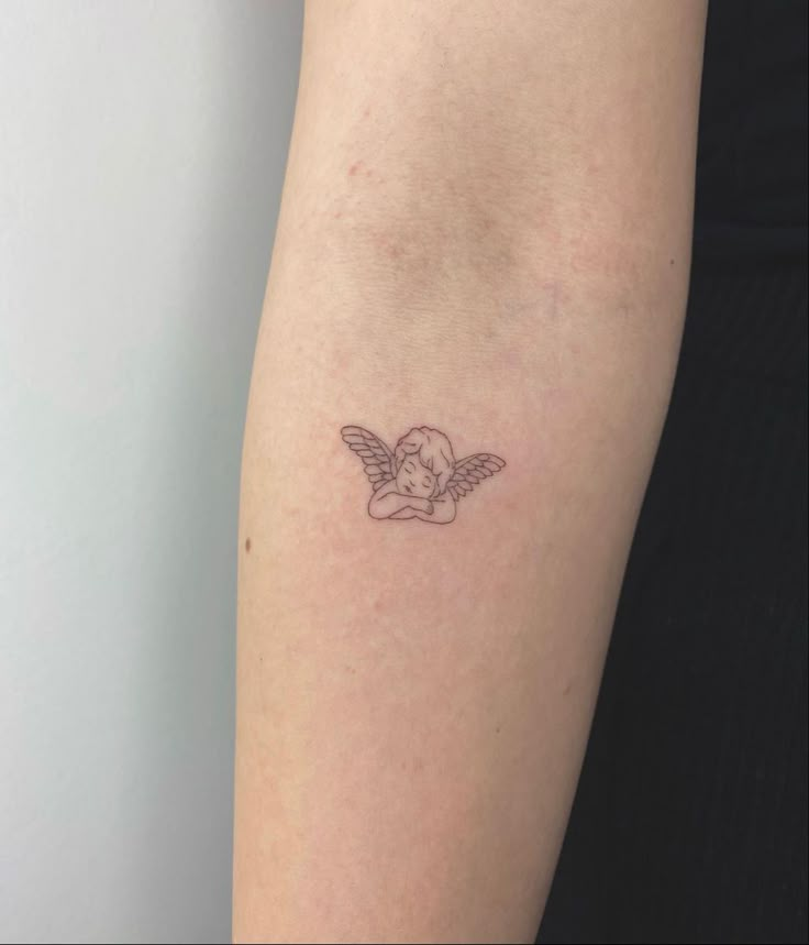 angel tattoo @chiko.tattoo Cherub Sleeping Tattoo, Small Fallen Angel Tattoo, Creation Of Adam Tattoo Fine Line, Dancing Angel Tattoo, Simple Cherub Tattoo, 2 Angels Tattoo, Fine Line Angel Tattoo, Minimalist Angel Tattoo, Breastbone Tattoo