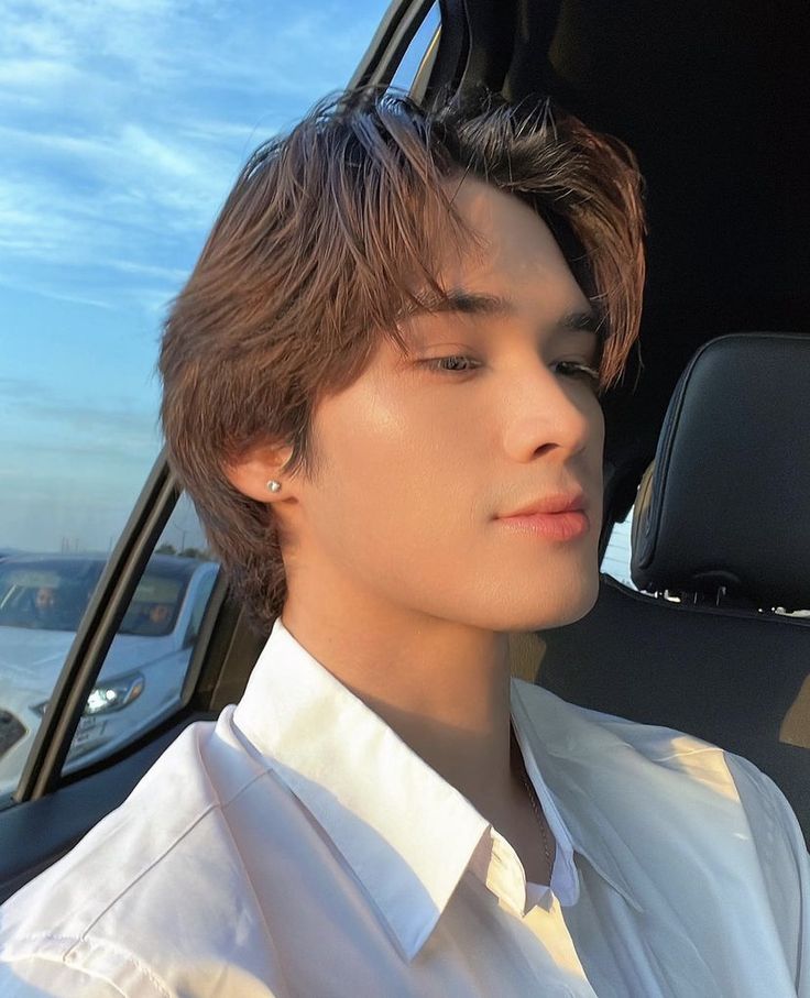 a young man sitting in the back seat of a car with his eyes closed, looking out the window