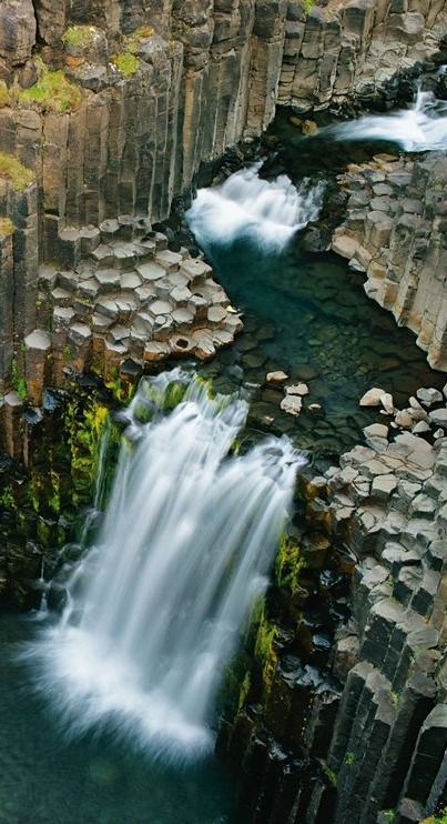 an aerial view of a waterfall in the middle of some rocks with water running down it