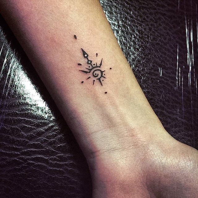 a small sun and moon tattoo on the wrist