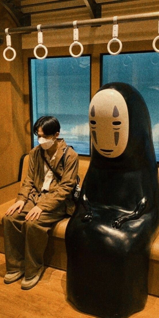 a man wearing a face mask sitting on a bench next to a large black object