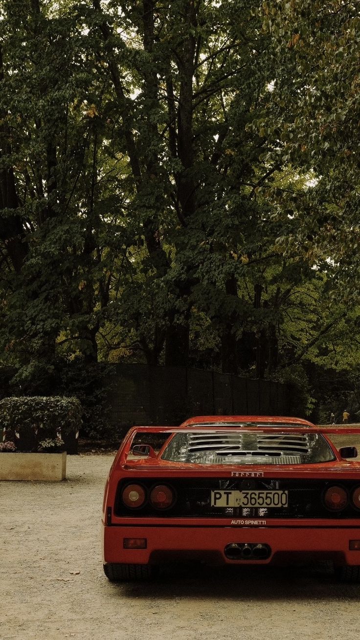 a red sports car parked in front of some trees