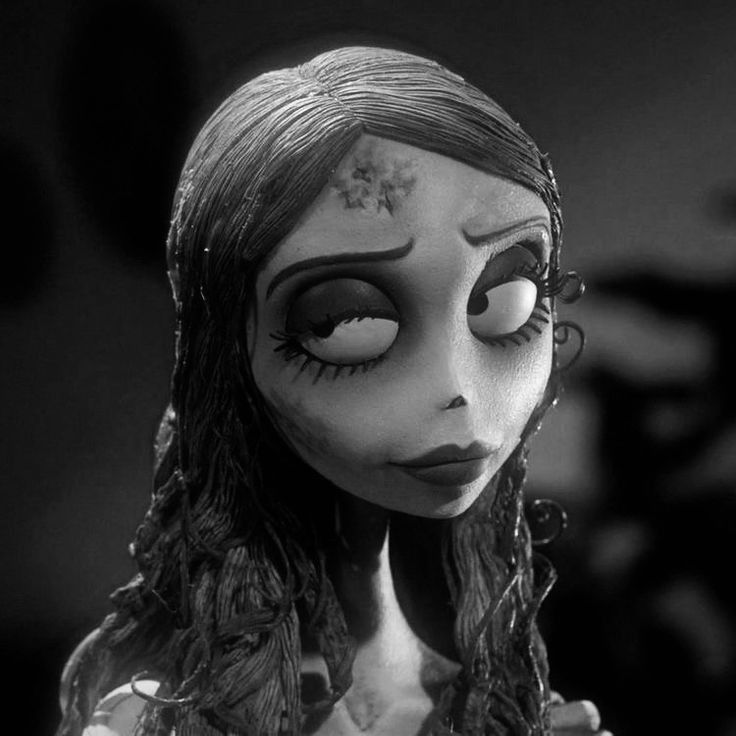 a creepy doll with long hair and makeup looks at the camera in a black and white photo