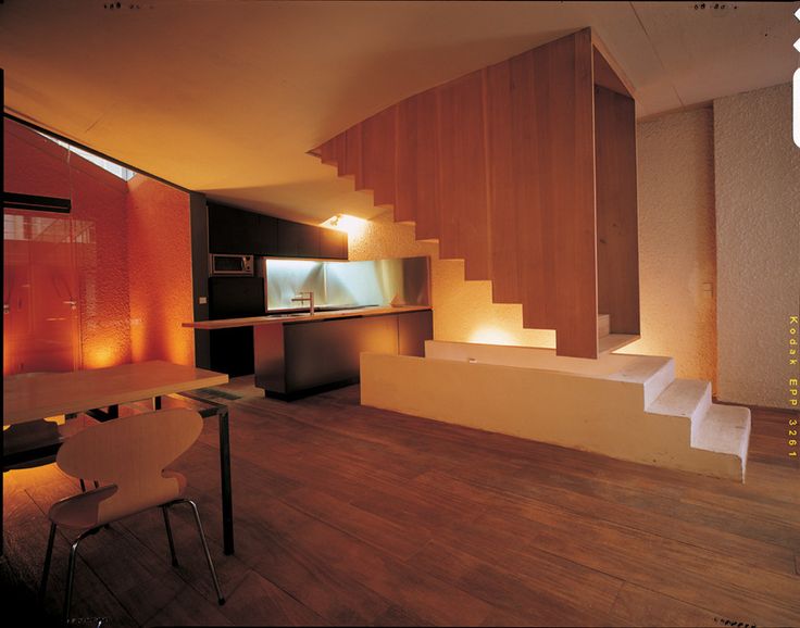 an empty room with stairs leading up to the kitchen