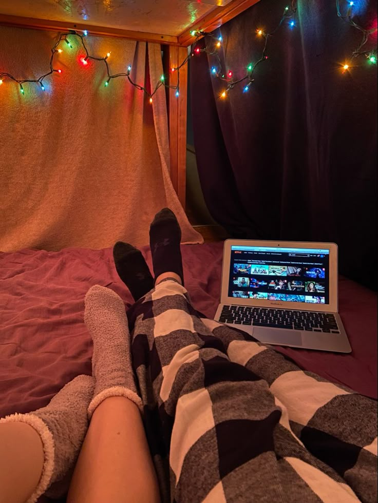 a person laying in bed with their feet up on a laptop