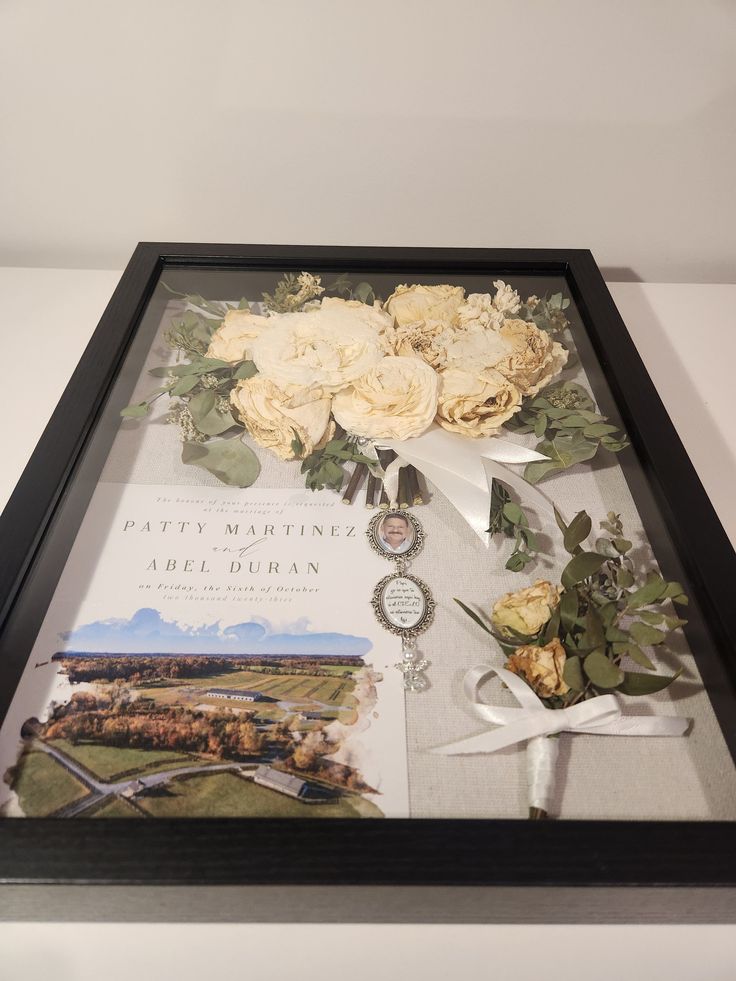 an arrangement of flowers is displayed in a shadow box with ribbon and bookmarks