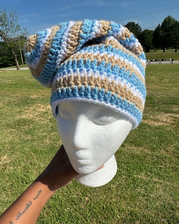 a white mannequin head wearing a blue and tan striped knitted beanie