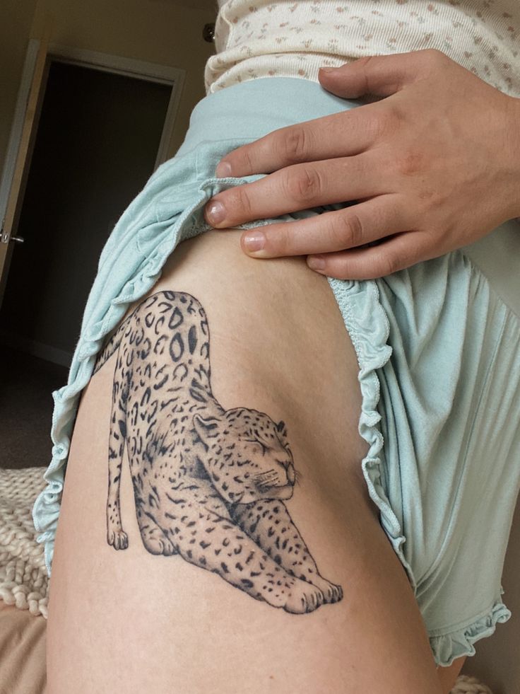 a woman's stomach with a tattoo of a cheetah sitting on it