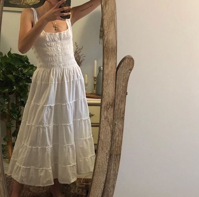 a woman taking a selfie in front of a mirror wearing a white dress and holding a cell phone