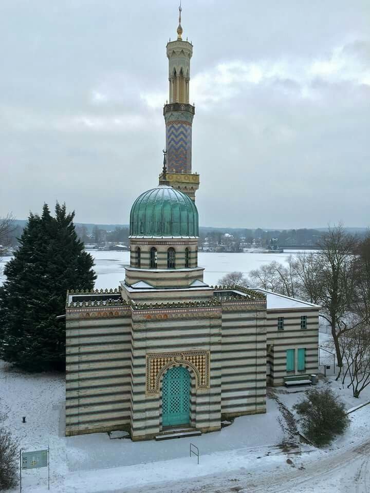 a large building with a green dome on top in the middle of snow covered ground