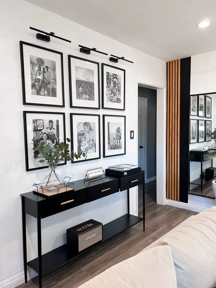 a living room filled with furniture and framed pictures on the wall above a table next to a couch