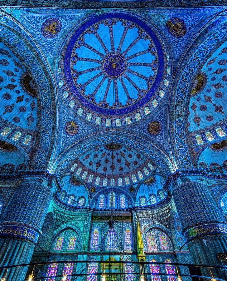 the inside of an ornate building with stained glass windows and blue ceiling tiles on the walls