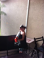 a young boy holding an orange and black object in his hand while standing on a patio