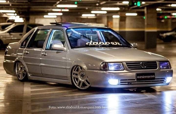 a silver car is parked in a parking garage with its lights on and it's hood up