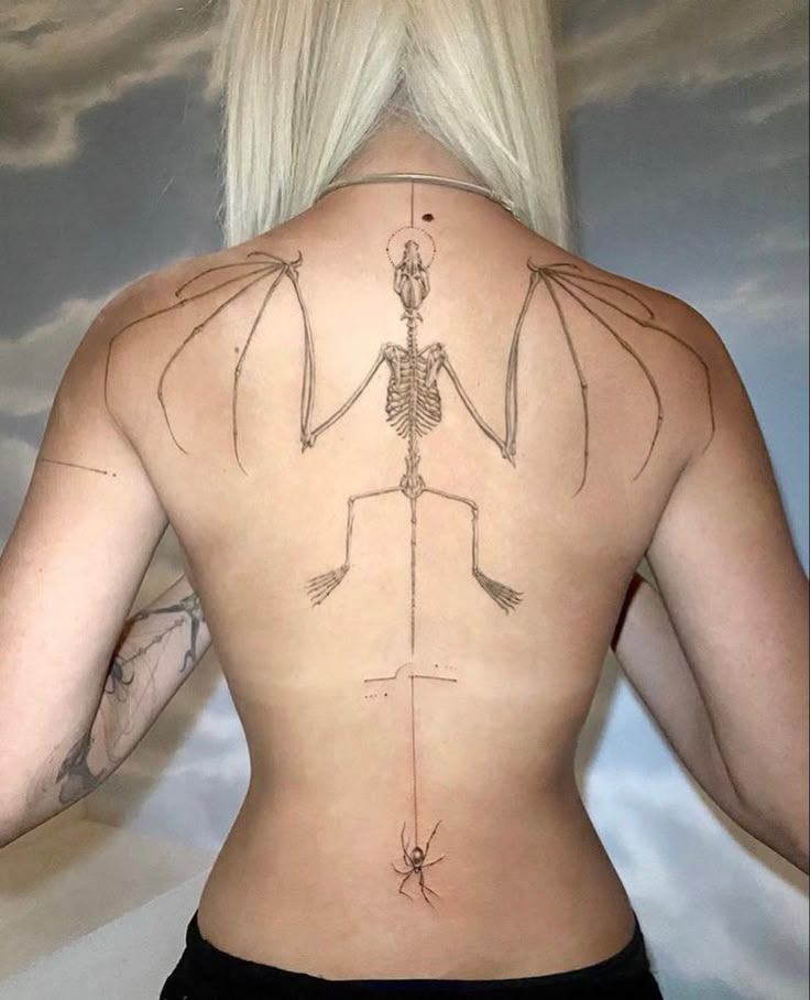 the back of a woman's body with an arrow and skeleton tattoo on it