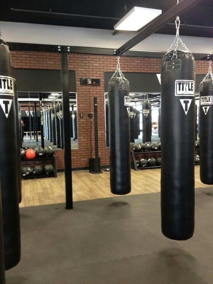 an empty gym with punching bags hanging from the ceiling and other equipment in the background