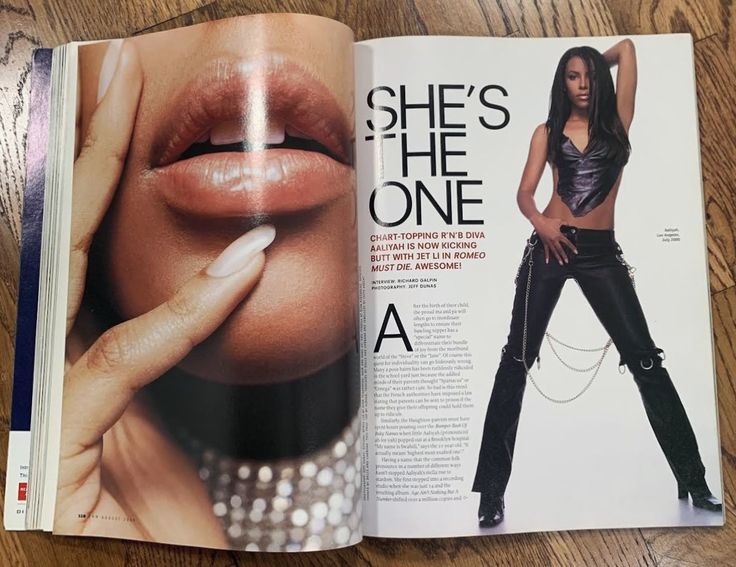 an open magazine with a woman's face and hands on the cover, in front of a wooden table