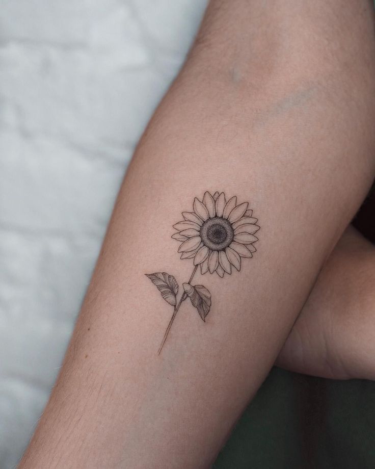 a woman's arm with a sunflower tattoo on it