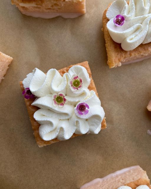 four pieces of cake with flowers on them sitting on a piece of wax paper next to each other