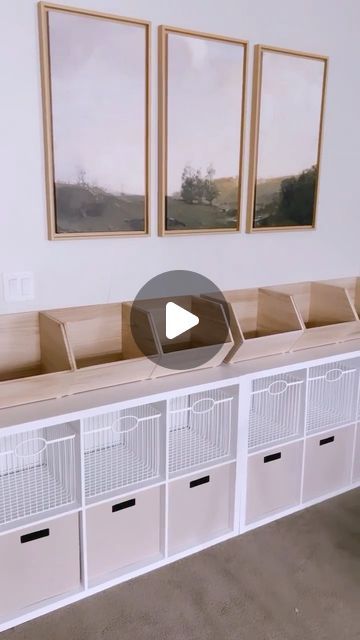 an empty room with several white storage bins and pictures on the wall above them