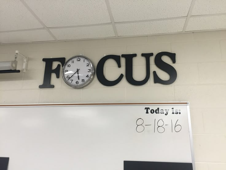 a clock mounted to the side of a wall next to a sign that says focus