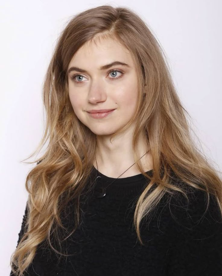 a woman with long blonde hair is posing for a photo in front of a white background