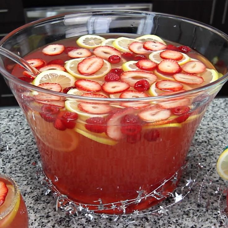 a large glass bowl filled with liquid and sliced strawberries