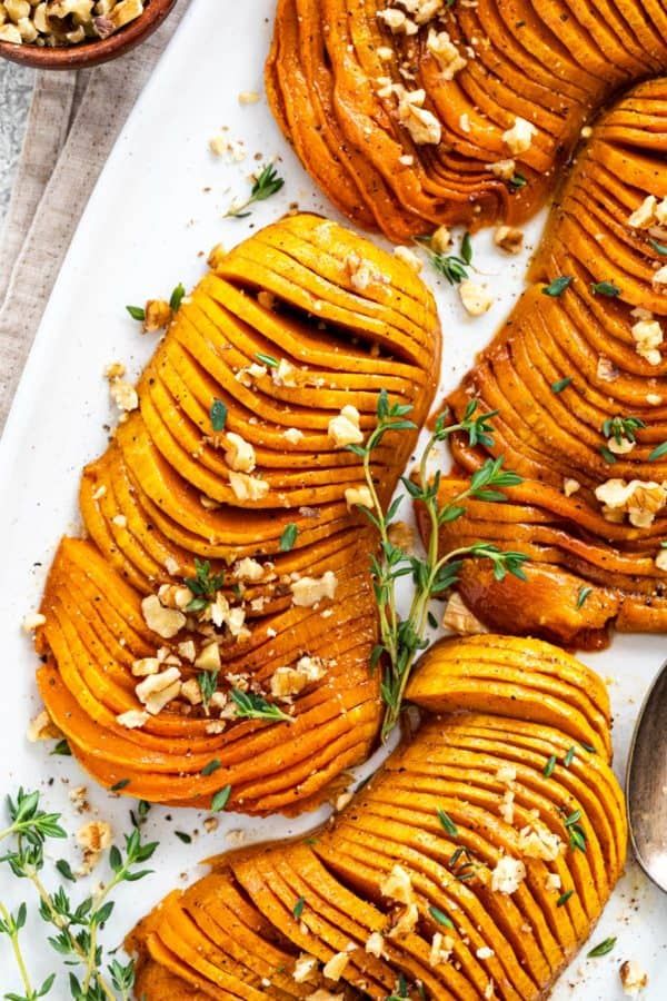 baked sweet potatoes with walnuts and herbs on a white platter